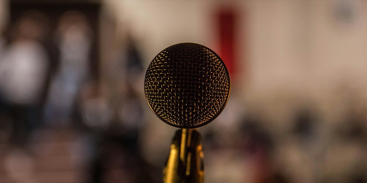 A microphone in front of a blurred audience of people