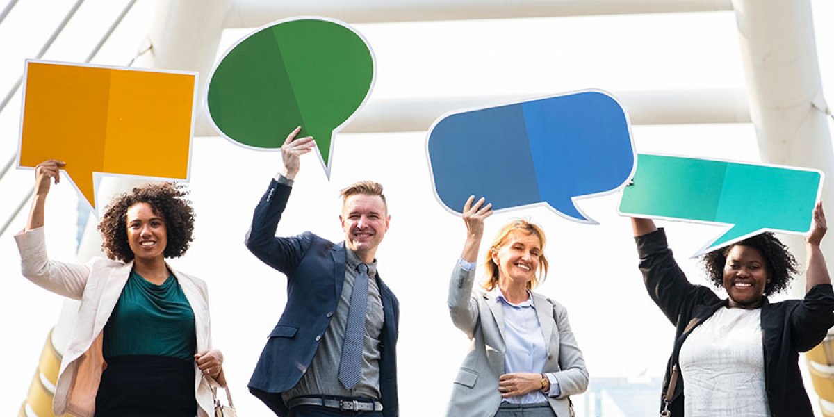Four people standing with speech bubble signs