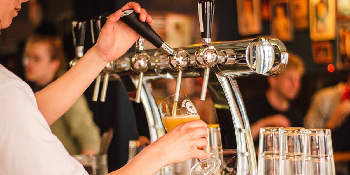 Photo of a pint of beer being poured in a busy pub