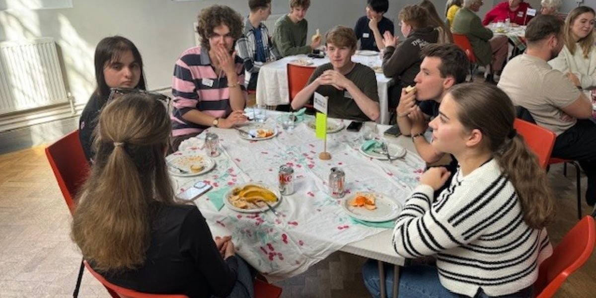 A group of freshers at a table talking and eating snacks