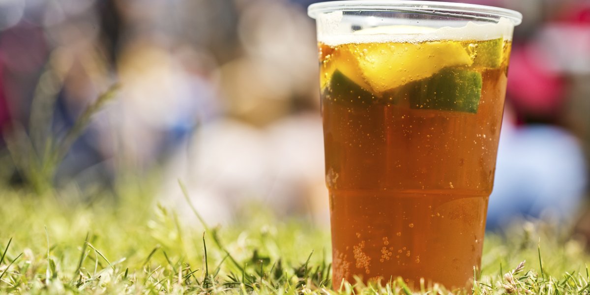 Plastic cup of drink in grass in the sunshine