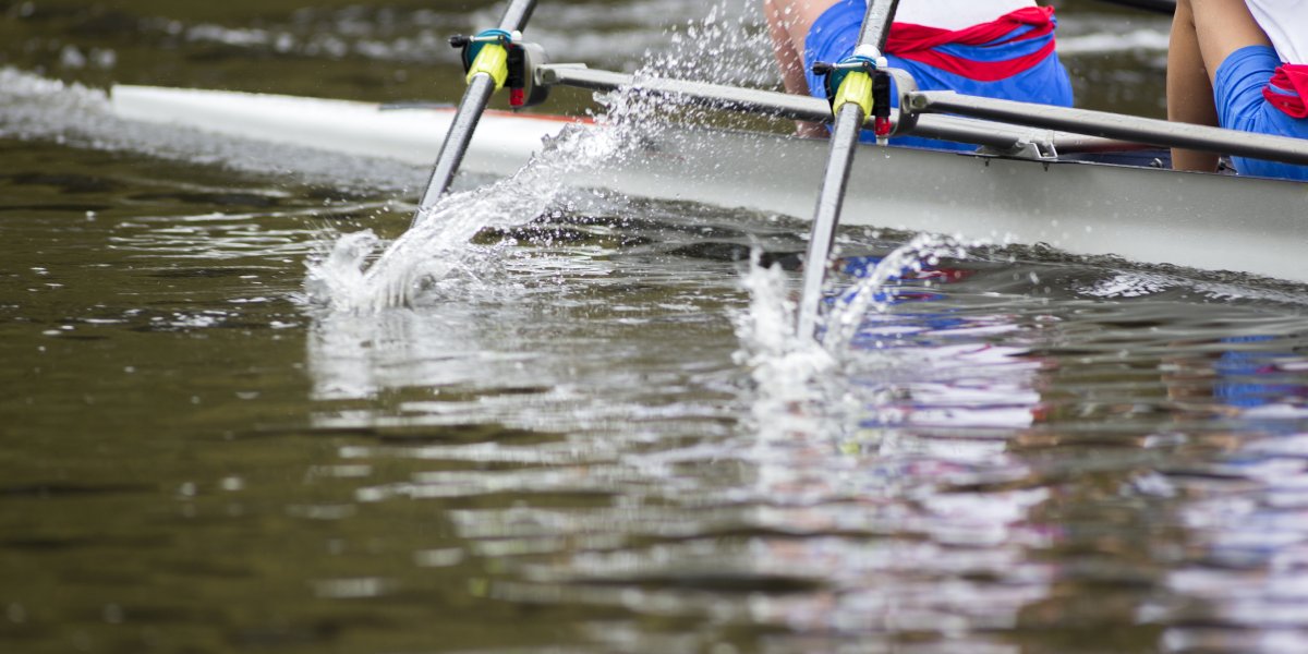 Rowers on a river, oars pierce the water