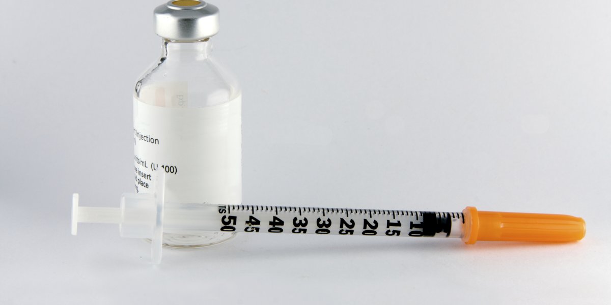 Syringe with a bottle of medication sit on a desk
