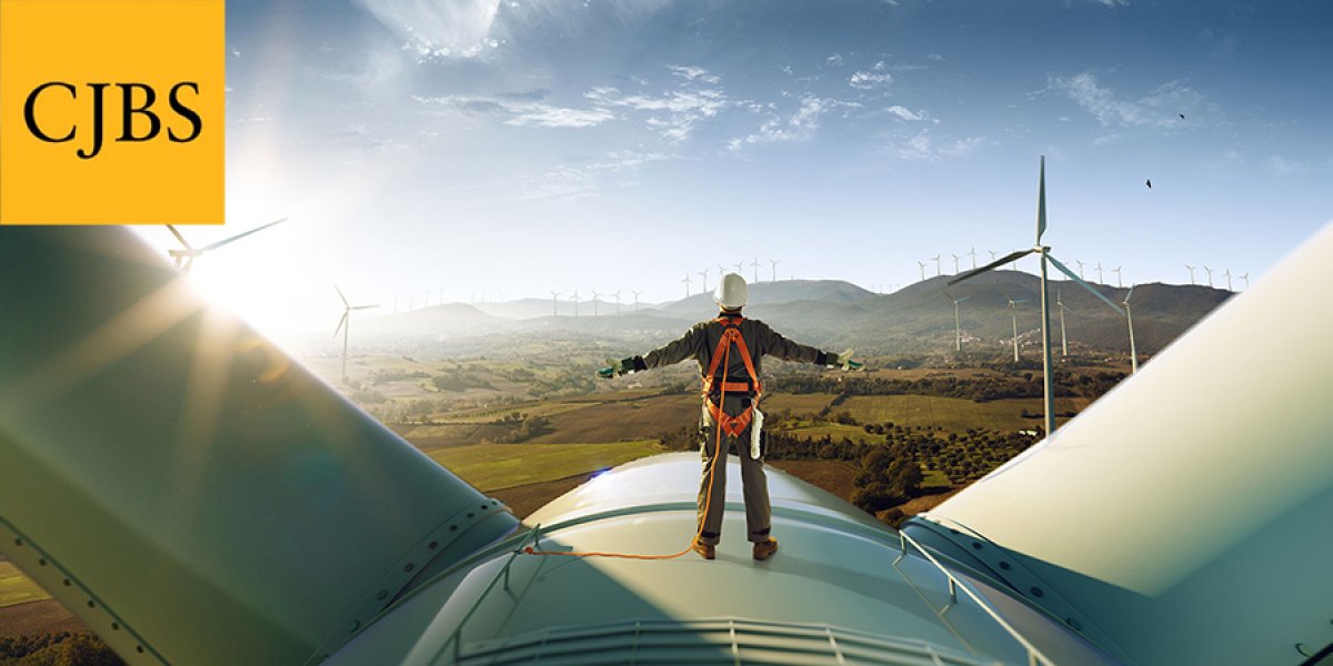 Man standing on top of a wind turbine with CJBS logo in top left corner