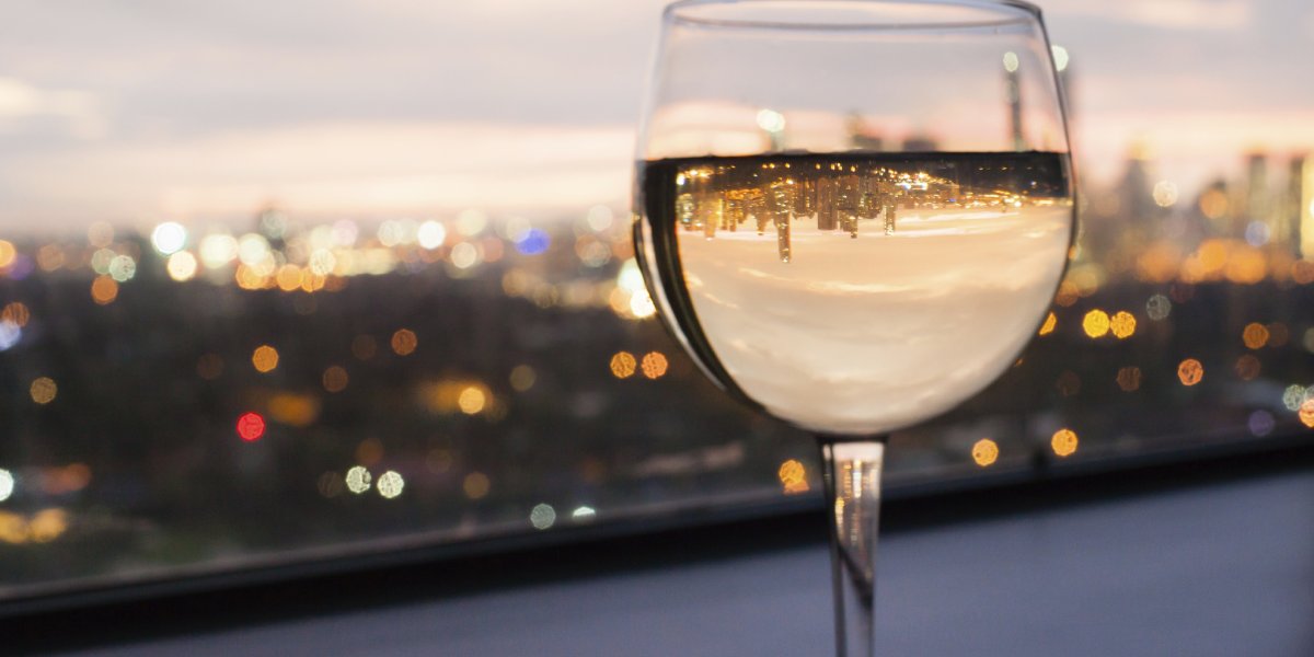 A glass of white wine in front of an evening city backdrop