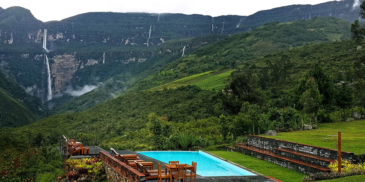 Pool terrace at Gocta Andes Lodge overlooking green mountains and a tall waterfall